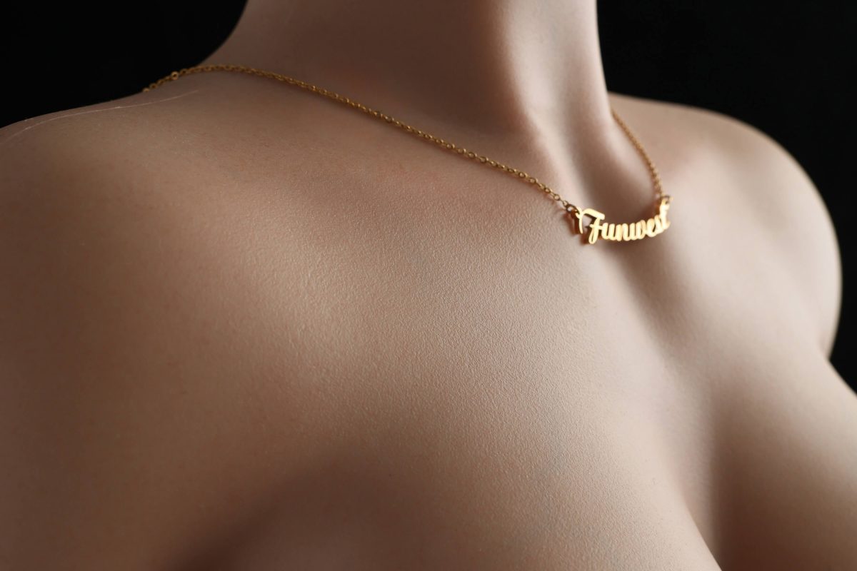 Close-up of a sophisticated gold necklace with a personalized "Fuwat" charm on a mannequin's neck.