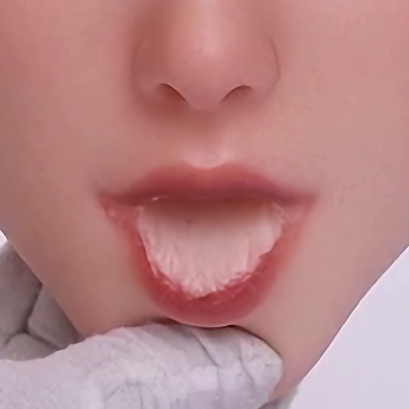 Close-up of a realistic doll's mouth showing detailed lips and tongue, emphasizing oral structure and texture.