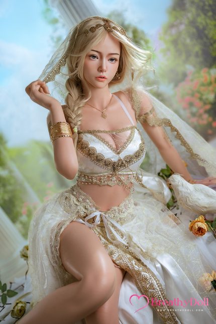 A woman dressed in an elegant, vintage-inspired lace and satin gown with intricate gold embroidery, posing outdoors with a soft, dreamy background.