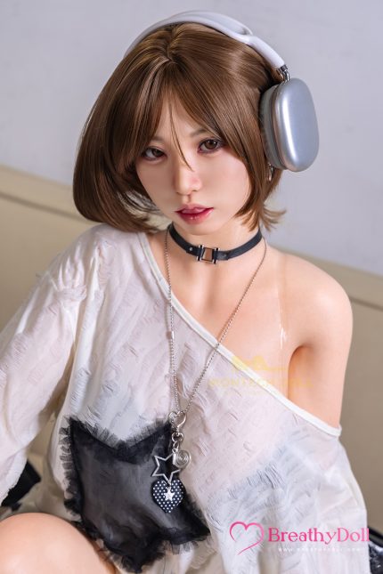 Young woman with short brown hair wearing large silver headphones, a choker, and a white off-shoulder top, sitting indoors.